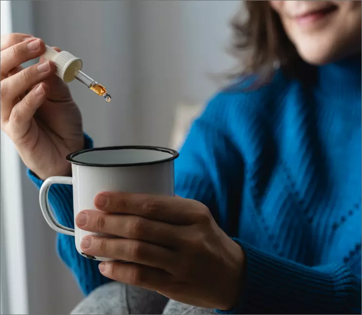 female dropping medicine into a cup of tea or coffee