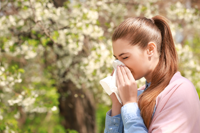 woman sneezing outside during allergy season